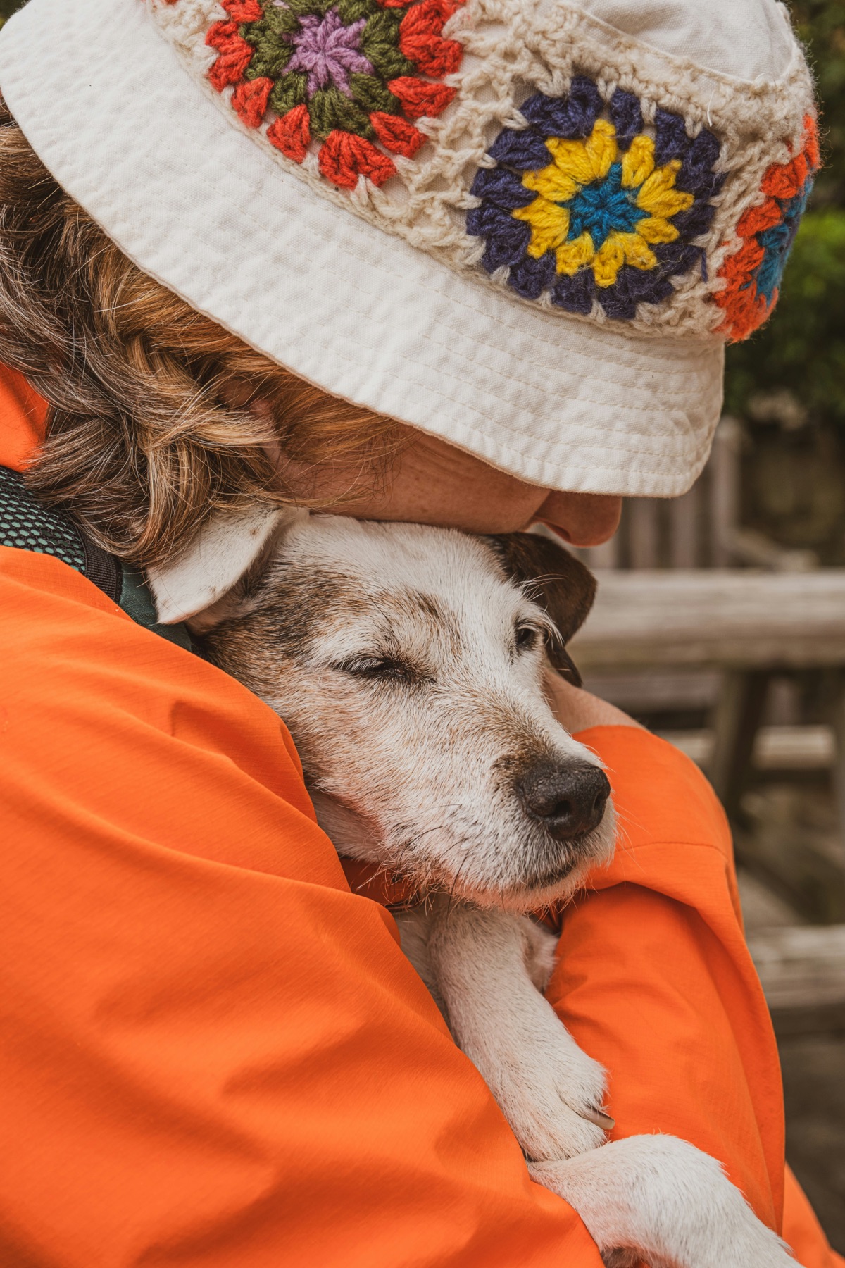 Pareja sonriendo y acariciando a su perro en exterior de montaña